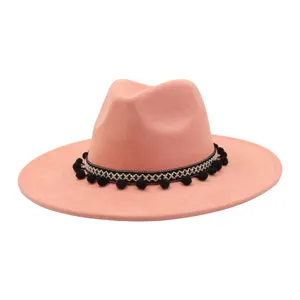 Close-up of pink faux suede jazz hat featuring ethnic black white band and cute black pom poms.