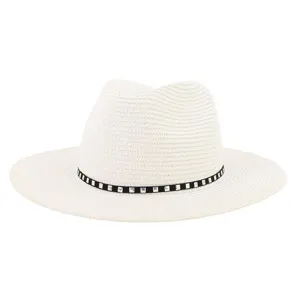 Gros plan détaillé du chapeau fedora en paille blanche avec une élégante bande cloutée noire.
