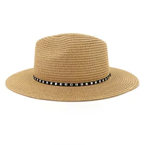 Vue détaillée du chapeau de paille kaki avec bande noire et clous métalliques carrés pour la plage.