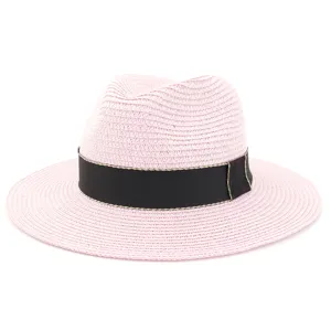 Détail de chapeau de paille rose, forme Fedora classique avec ruban noir et bord doré.