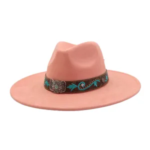 Detalle de sombrero fedora rosa de ante con ala ancha, banda étnica bordada y hebilla de plata.