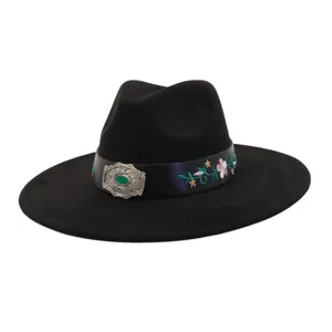 Close-up of the exquisite floral embroidery and ornate silver buckle on the black wide-brim hat.