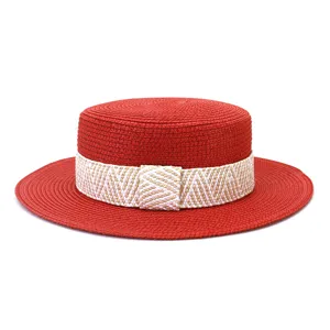 Detailed view of red straw boater hat with beige woven band, ideal for summer sun protection.