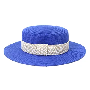 Detailed view of a stylish blue flat-top straw hat with a woven patterned band for summer outdoor travel.