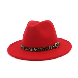 Primer plano de sombrero fedora de lana roja con cinturón de leopardo y hebilla elegante.