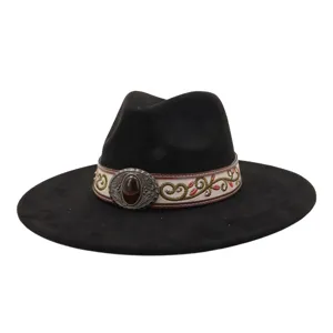Detailed view of black wide-brim fedora hat with embroidered band and gemstone buckle.