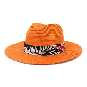 Detailansicht eines orangefarbenen Strohhutes mit schwarzem tropischen Blumenband für Strand.
