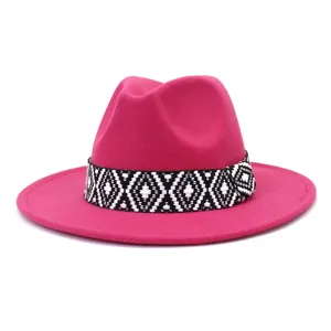 Vista detallada del sombrero fedora rosa de fieltro con una banda tejida geométrica.