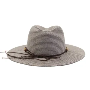 Close-up detail view of the woven straw sun hat, featuring stylish brown rope and wood bead decor.