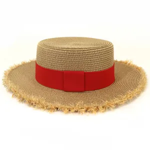 Detaillierte Ansicht des flachen Strohhuts für Damen mit rotem Band und ausgefranstem Rand.