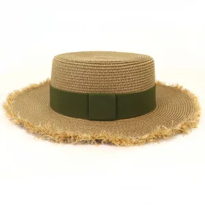 Detailaufnahme eines flachen Damen-Strohhutes mit gruenem Band und ausgefransten Kanten.