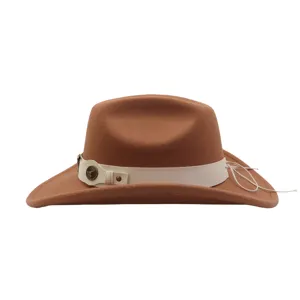 Detail view of brown felt cowboy hat with white band and western metal bull head emblem.