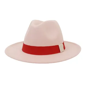 Gros plan d'un chapeau fedora en laine rose clair avec un ruban rouge remarquable.