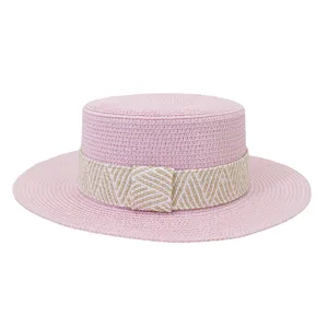 Details of the pink straw flat top sun hat featuring a beige woven band and breathable weave.