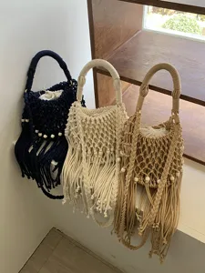 Primo piano della borsa a tracolla intrecciata a mano con frange e perline di legno.