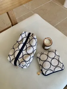 Detailed view of retro embroidered cosmetic bag and coin pouch set with elegant circular pattern.