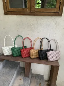 Detailed shot of multi-color woven straw tote beach bags arranged neatly on rustic bench.
