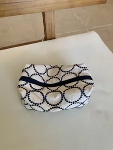 Detailed shot of embroidered fabric cosmetic bag with blue circle pattern, zipper closure.