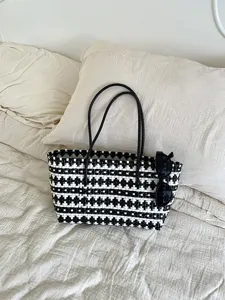 Detailansicht der schwarz-weißen geflochtenen Tasche mit geometrischem Muster und Textur.