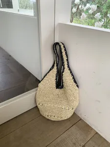 Vue détaillée du sac d'été en paille tissée sous le bras, joli tissu beige texturé naturel.