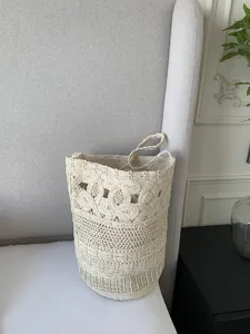 Dettaglio della borsa a secchiello in macramè beige intrecciato con motivo traforato.