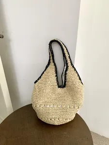Vue détaillée de sac à épaule en paille, design décontracté noir et blanc d'été.
