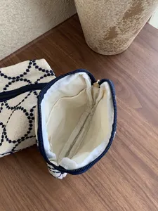 Canvas cosmetic pouch with blue geometric embroidery and zipper closure for daily use.