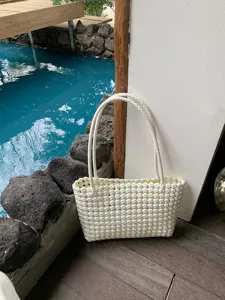 White plastic woven tote bag, hollow beach bag detail view, ideal for summer resort vacation.