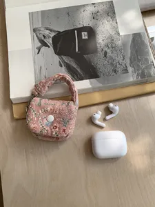 Detail view of a pink embroidered floral mini headphone storage bag with handle and snap closure.