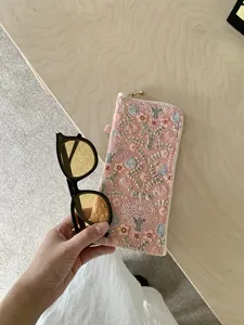 Detailed view of portable embroidered sunglasses case, stylish floral design pouch storage.