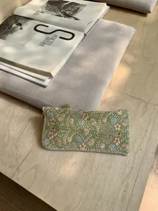 Detailed shot of green embroidered glasses pouch featuring intricate floral patterns.