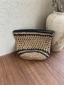 Bolso cosmetico tejido a mano de paja con rayas negras y detalle de cremallera elegante.
