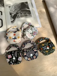 Detailed view of mini embroidered earphone storage pouch with floral pattern and handle.