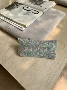 Embroidered glasses pouch detail showing delicate floral stitching and fabric texture.