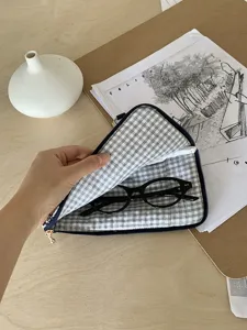 Close-up detail view of plaid fabric glasses storage pouch interior with black eyeglasses inside.