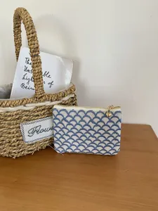 Detailansicht der Leinen bestickten Münztasche mit blauem Wellenmuster und Goldreißverschluss.