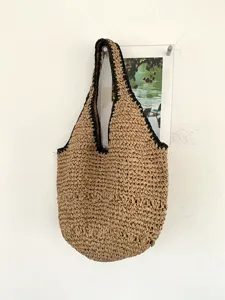 Vue détaillée du sac d'épaule en paille tissée avec texture naturelle et bordure noire.