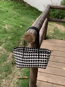 Nahaufnahme Detail der schwarz-weißen gewebten Tasche an einem hölzernen Geländer außen.