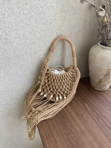 Vista dettagliata della borsa a secchiello traforata intrecciata a mano con nappe.