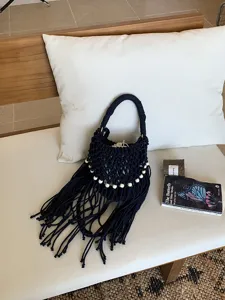 Primo piano dettagliato di borsa a tracolla in macramè con frange e perline di legno.