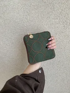 Detail shot of dark green fabric embroidered small pouch with retro circular pattern zipper.