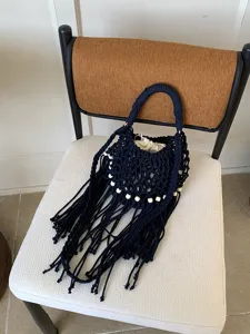 Vista dettagliata della borsa a secchiello in macramè blu scuro con frange e perline di legno.