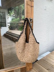 Vue détaillée du sac en paille tissé suspendu à la poignée de porte, style estival.