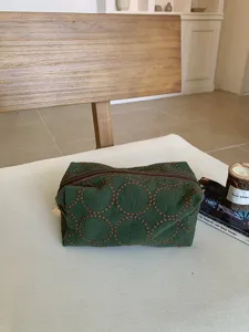 Dark green fabric cosmetic bag with embroidered circle pattern, vintage style makeup pouch.