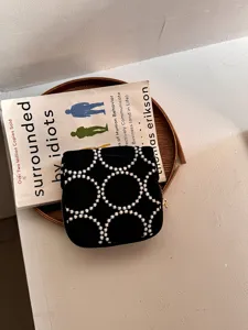 Gedetailleerde close-up van zwart geborduurd stoffen sieradenzakje met geometrische patronen.