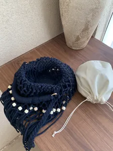 Vista dettagliata della borsa a tracolla intrecciata a mano con perline e pochette.