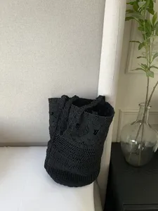 Dettaglio borsa a secchiello intrecciata macramè nera, borsa mare spalla vacanza tote.