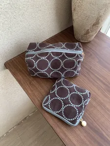 Detailed view of brown fabric cosmetic pouches with white embroidered circular patterns.