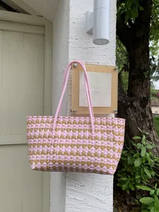 Detailaufnahme einer rosa-beigen geflochtenen Korbtasche mit feinem Lochmuster und Henkeln.