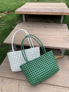 Woven plastic tote bag detail, hollow mesh beach handbag, green and white summer design.